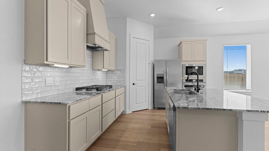 Bright and spacious kitchen with quartz countertops, stainless steel appliances, and an island with bar seating.