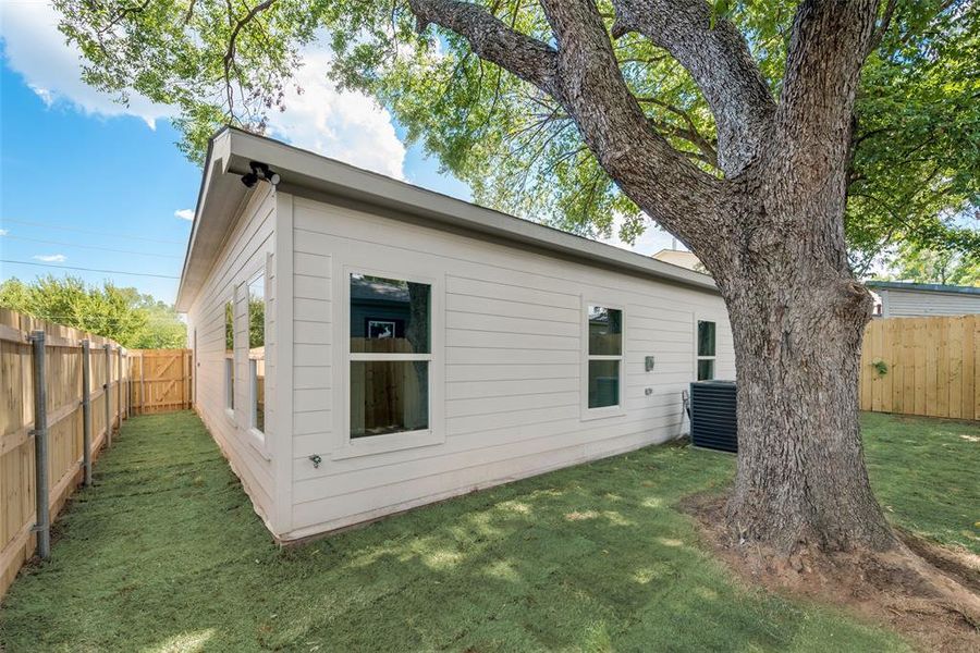 Rear view of house with central AC unit and a lawn