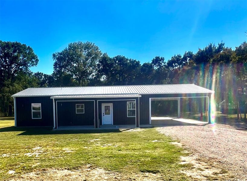 View of front of property with an attached carport, board and batten siding, a metal roof, and a front lawn View of front of property with an attached carport, board and batten siding, a metal roof, and a front lawn