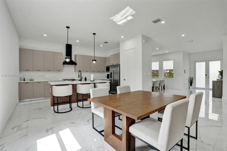 Gourmet kitchen with sleek cabinetry, white countertops, and a central island with bar seating