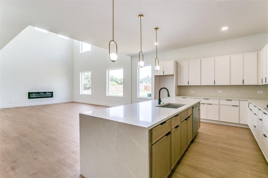 Kitchen featuring dishwasher, light wood-type flooring, a center island with sink, white cabinetry, and recessed lighting Kitchen featuring dishwasher, light wood-type flooring, a center island with sink, white cabinetry, and recessed lighting