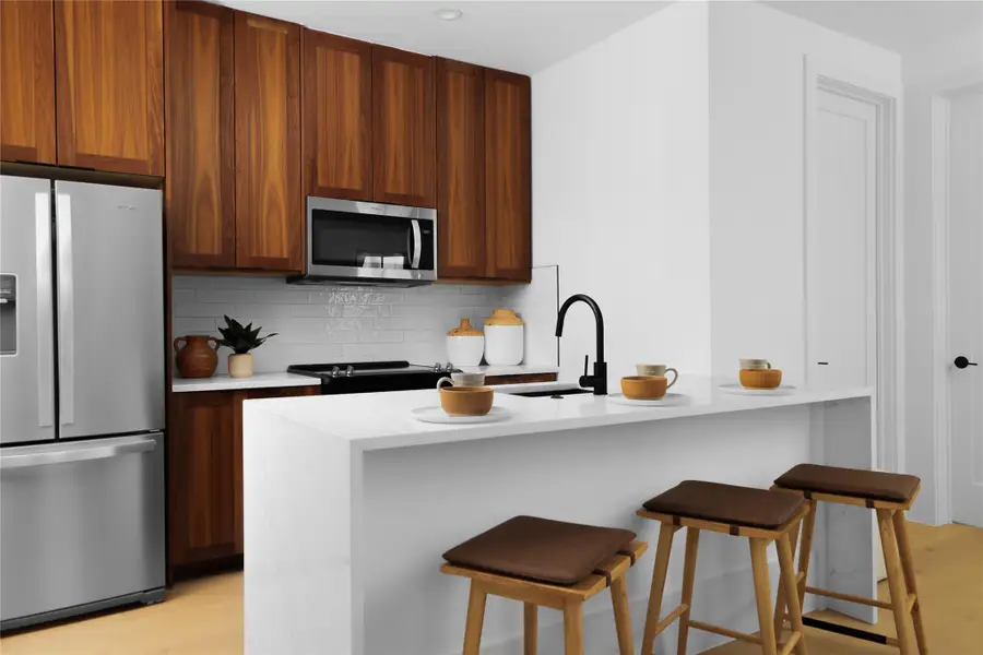 Kitchen with stainless steel appliances, light wood finished floors, backsplash, and light countertops Kitchen with stainless steel appliances, light wood finished floors, backsplash, and light countertops