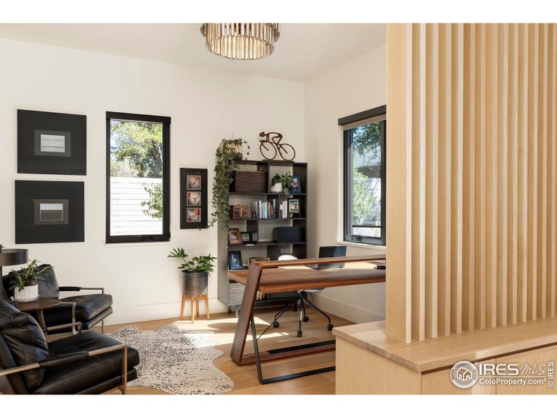 A flexible office or lounge, defined by vertical oak slats and custom cabinetry, sits just off the main living space. A flexible office or lounge, defined by vertical oak slats and custom cabinetry, sits just off the main living space.