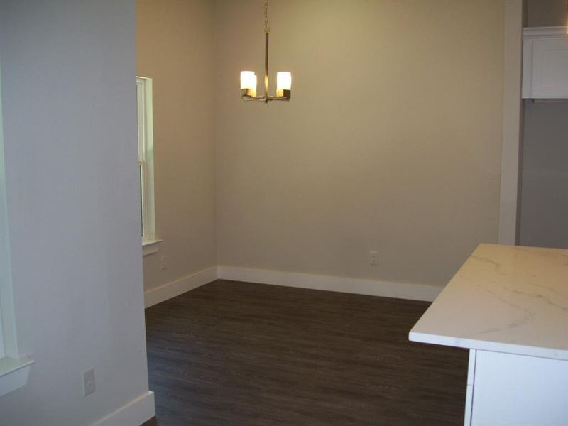 Unfurnished dining area with dark wood-type flooring and a chandelier