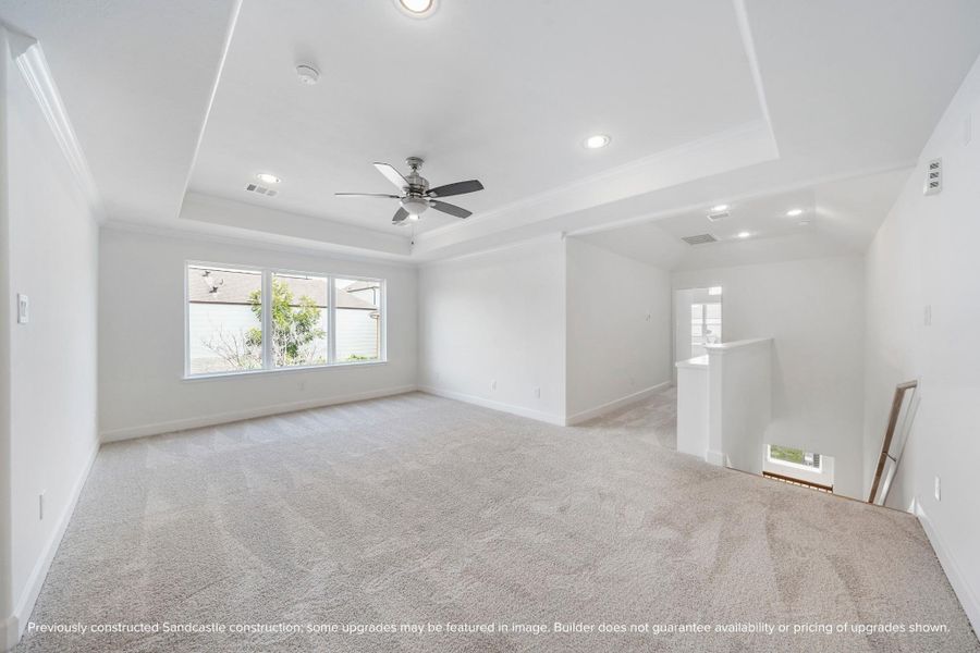 Let the fun begin in this vibrant game room, with a tray ceiling, ceiling fan, and a wall of windows flooding the space with light.