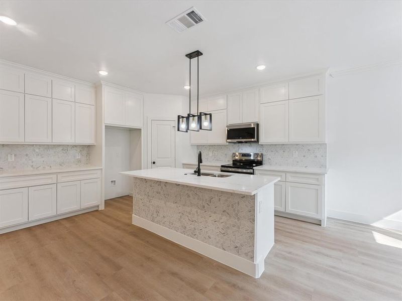 Kitchen featuring backsplash, light stone countertops, pendant lighting, white cabinets, and recessed lighting