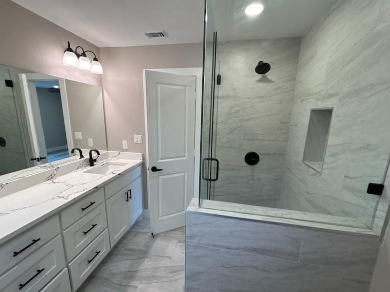 Full bath featuring vanity, a marble finish shower, and recessed lighting Full bath featuring vanity, a marble finish shower, and recessed lighting