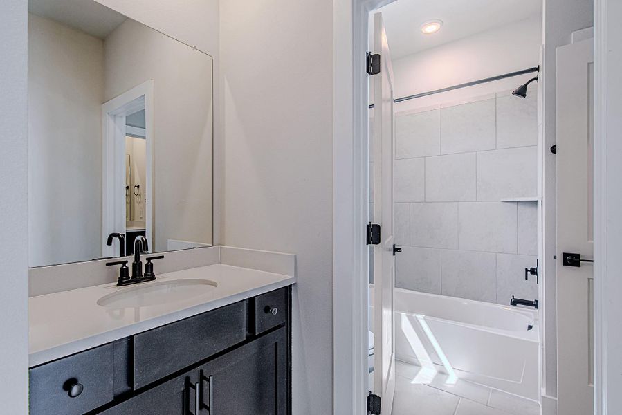 Full bathroom featuring a dark vanity and glass-enclosed shower