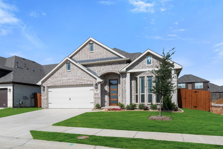 Single-story brick home with two-car garage, arched entry, and manicured front lawn