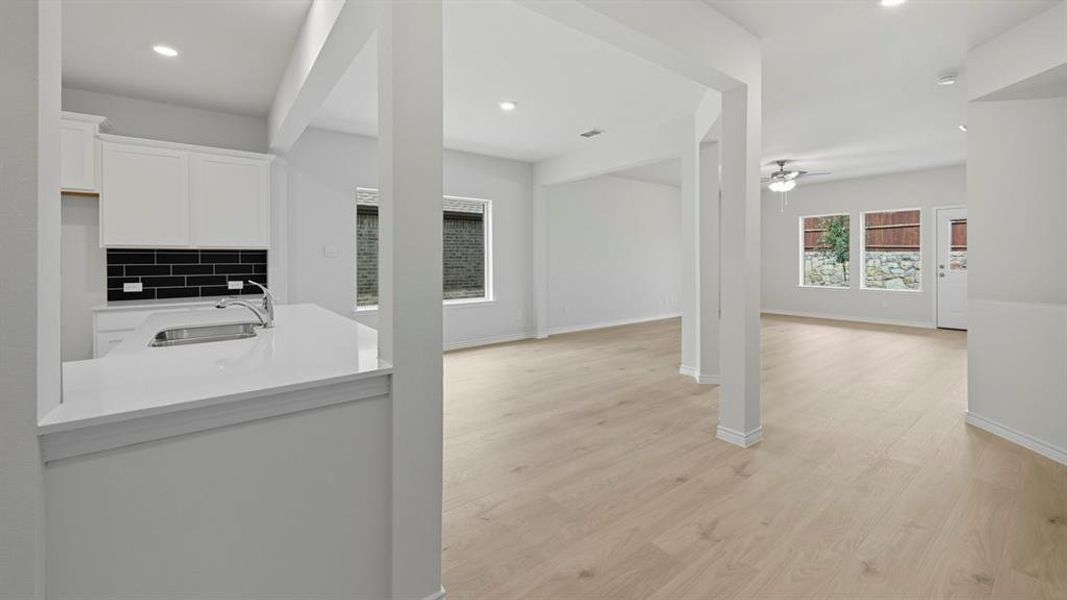 Kitchen with white cabinets, light stone countertops, tasteful backsplash, light wood-style flooring, and recessed lighting Kitchen with white cabinets, light stone countertops, tasteful backsplash, light wood-style flooring, and recessed lighting