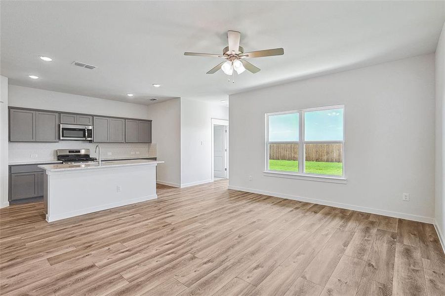 Kitchen with light hardwood / wood-style flooring, an island with sink, gray cabinetry, ceiling fan, and stainless steel appliances