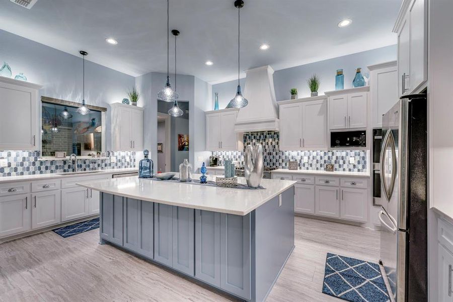 Kitchen featuring custom exhaust hood, large sink with window looking out to the pool
