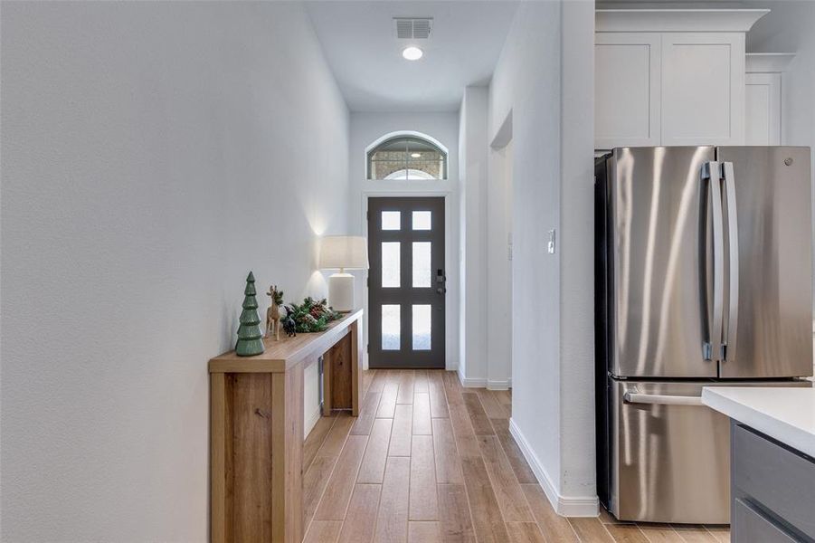 Foyer entrance with light wood-type flooring and a towering ceiling