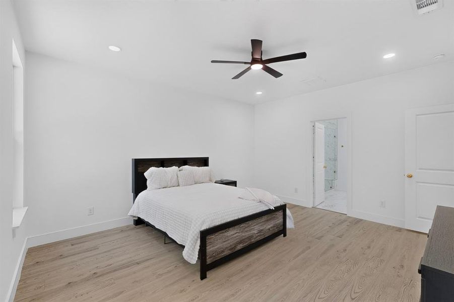 Bedroom featuring light wood-finish flooring, recessed lighting, and a dark-toned ceiling fan