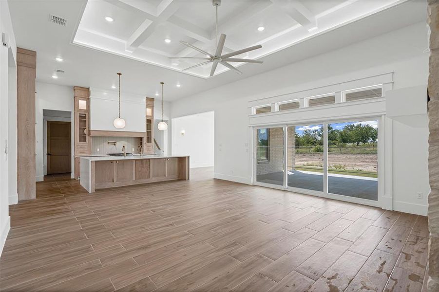 Unfurnished living room with coffered ceiling, beamed ceiling, a ceiling fan, a high ceiling, and recessed lighting Unfurnished living room with coffered ceiling, beamed ceiling, a ceiling fan, a high ceiling, and recessed lighting