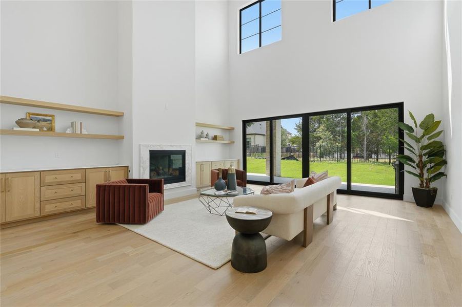 Spacious living area featuring high ceilings, light wood-finish flooring, and a fireplace with a light-toned surround