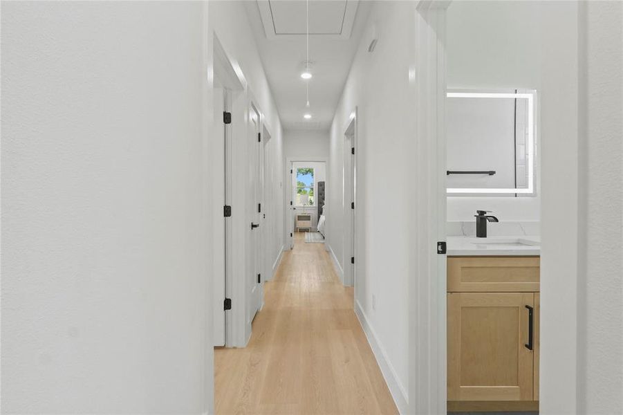 Corridor with attic access, light wood-style floors, and recessed lighting Corridor with attic access, light wood-style floors, and recessed lighting