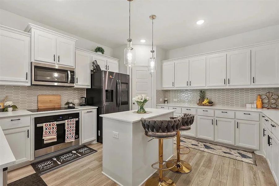 Kitchen featuring hanging light fixtures, tasteful backsplash, white cabinets, a kitchen island, and appliances with stainless steel finishes