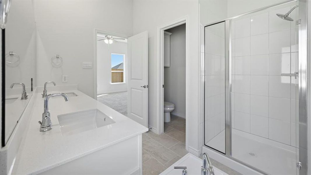 Full bath featuring double vanity, a stall shower, and ceiling fan