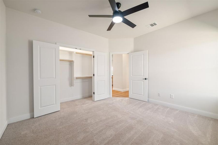 Unfurnished bedroom featuring carpet, a closet, and a ceiling fan