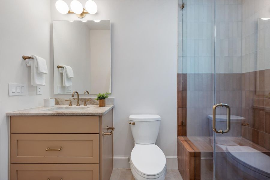Sleek glass-enclosed shower highlights this modern bathroom with neutral finishes and clean lines.