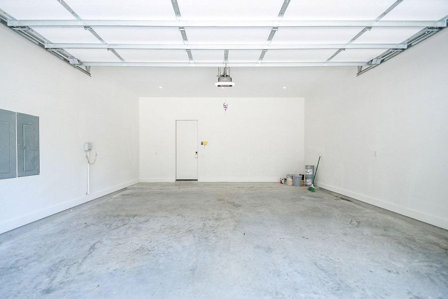 This spacious, clean garage features a fresh white interior with ample room for two cars. It's equipped with overhead storage potential and convenient access to the main house.
