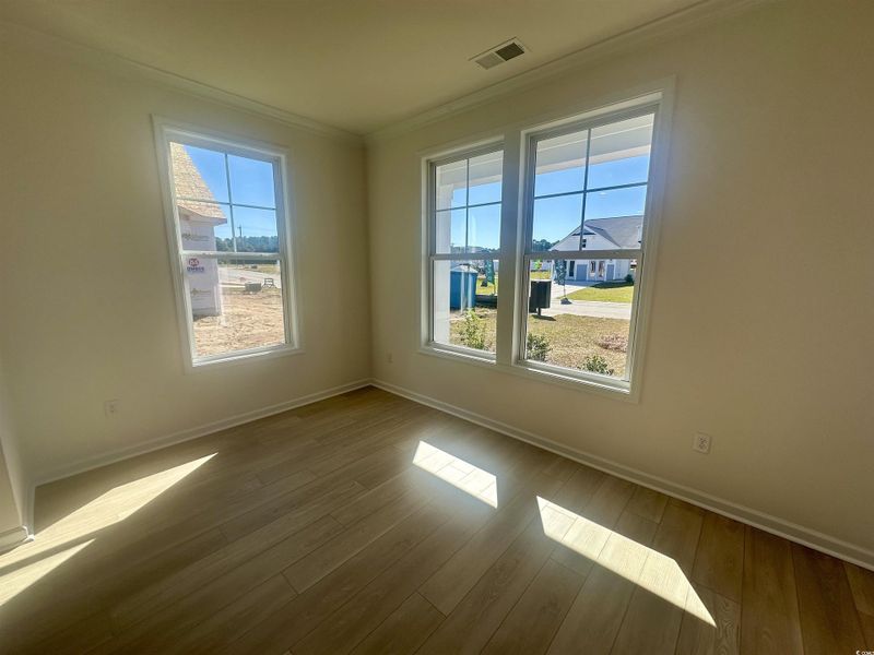 Unfurnished room featuring ornamental molding, healthy amount of natural light, and wood finished floors Unfurnished room featuring ornamental molding, healthy amount of natural light, and wood finished floors