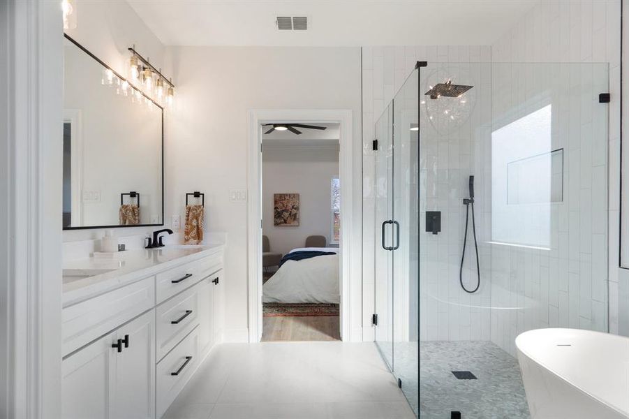 Ensuite bathroom featuring double vanity, a freestanding tub, a stall shower, ceiling fan, and plenty of natural light Ensuite bathroom featuring double vanity, a freestanding tub, a stall shower, ceiling fan, and plenty of natural light