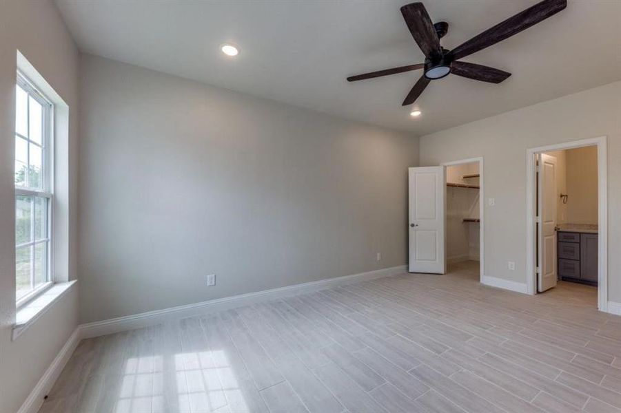 Unfurnished bedroom featuring a spacious closet, connected bathroom, a closet, and ceiling fan