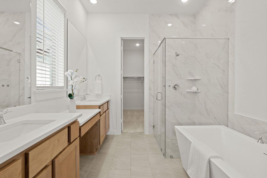 Experience luxury in this expansive primary bathroom, complete with a stunning stand alone tub, glass framed walk-in shower, sleek quartz countertops, and contemporary tile accents — the perfect oasis for relaxation and rejuvenation.