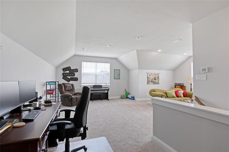 Office area featuring light carpet, lofted ceiling, and baseboards Office area featuring light carpet, lofted ceiling, and baseboards