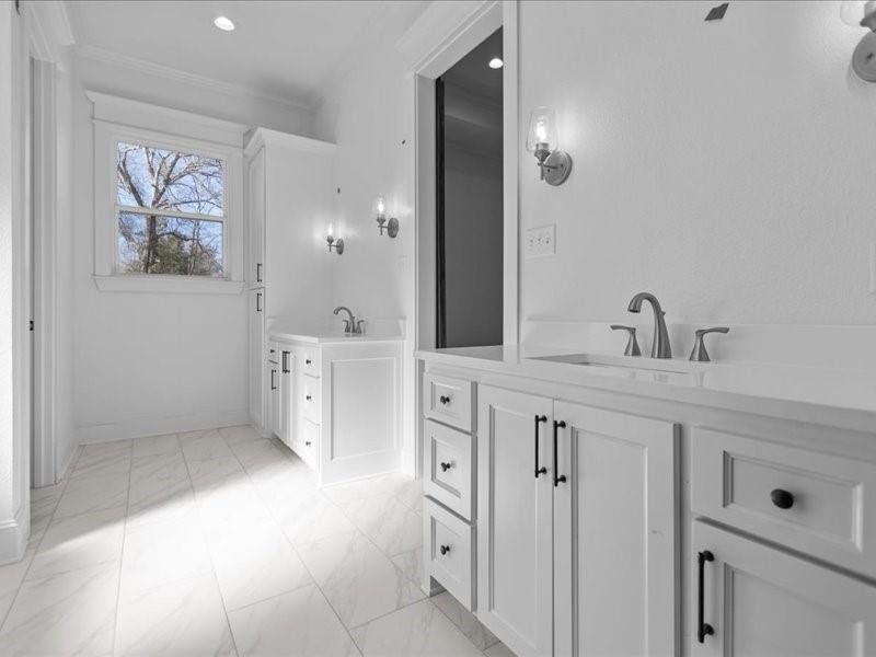 Bathroom featuring two vanities, light marble finish floors, recessed lighting, and ornamental molding