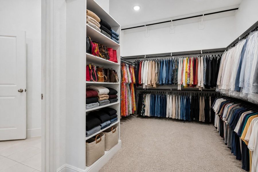 Primary bedrooms closet with built in shelving and plenty of hanging space.