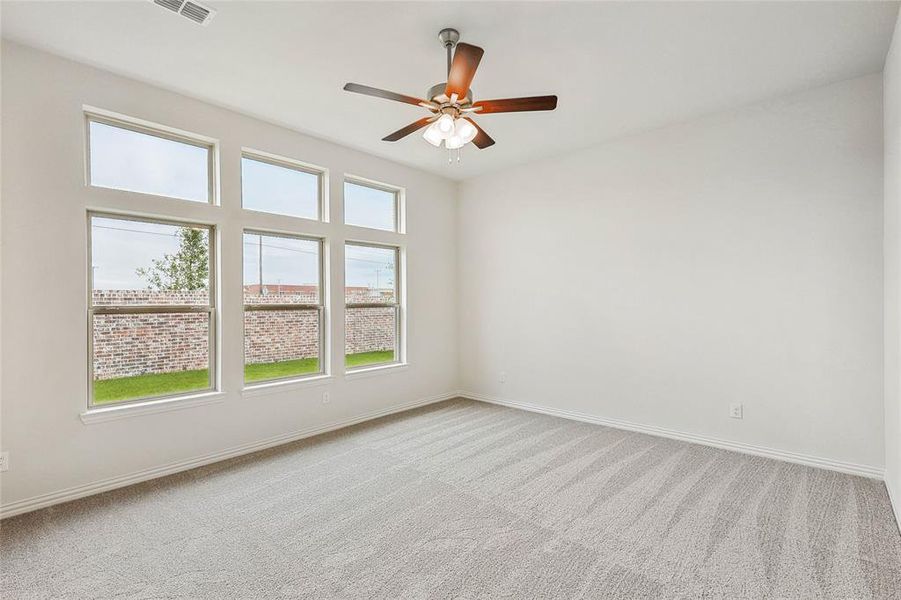 Carpeted spare room with plenty of natural light and ceiling fan