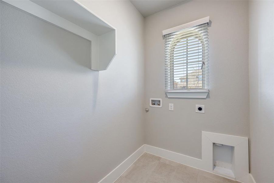 Laundry area featuring electric dryer hookup, washer hookup, and light tile patterned flooring