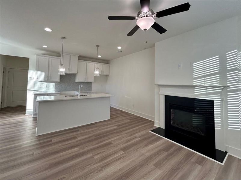 Kitchen with ceiling fan, an island with sink, decorative light fixtures, and light hardwood / wood-style floors