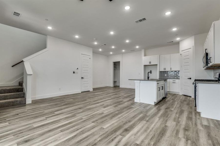 Kitchen featuring sink, white cabinetry, an island with sink, and light hardwood / wood-style flooring