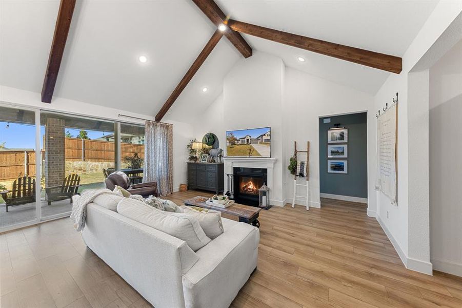 Vaulted ceiling with wood beams, triple-slider doors, and natural light throughout the open-concept living space ,with gas fireplace.