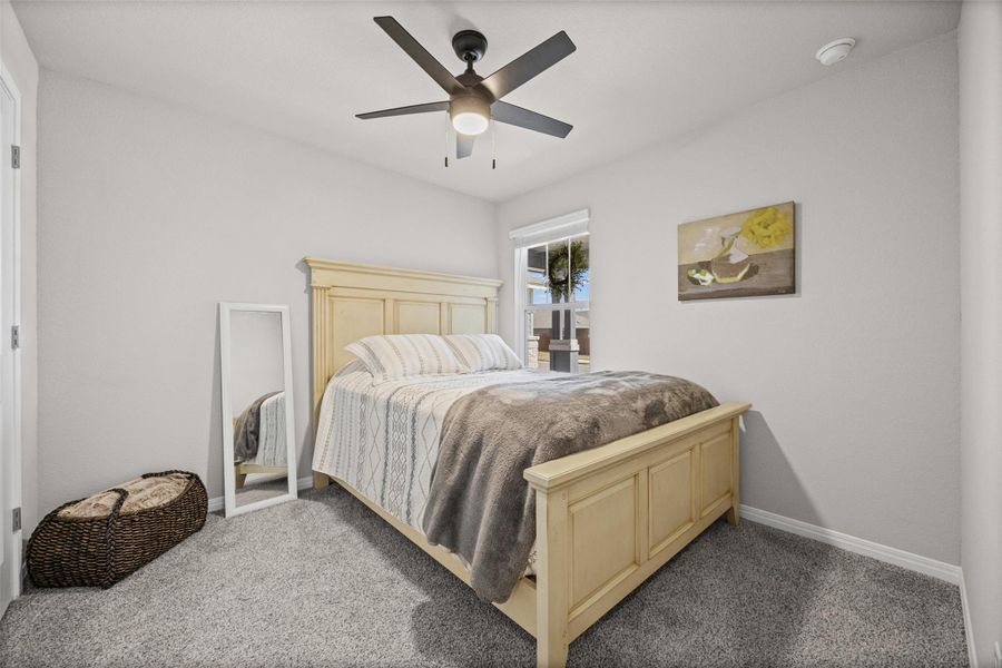 Soft carpeting underfoot and a tall window bring warmth to this comfortable bedroom space.