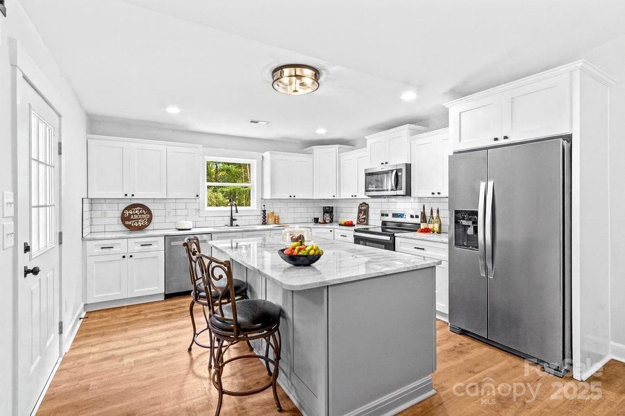 Dream Kitchen with marble counters, stainless appliances & LVP flooring. (The refrigerator was virtually added.)