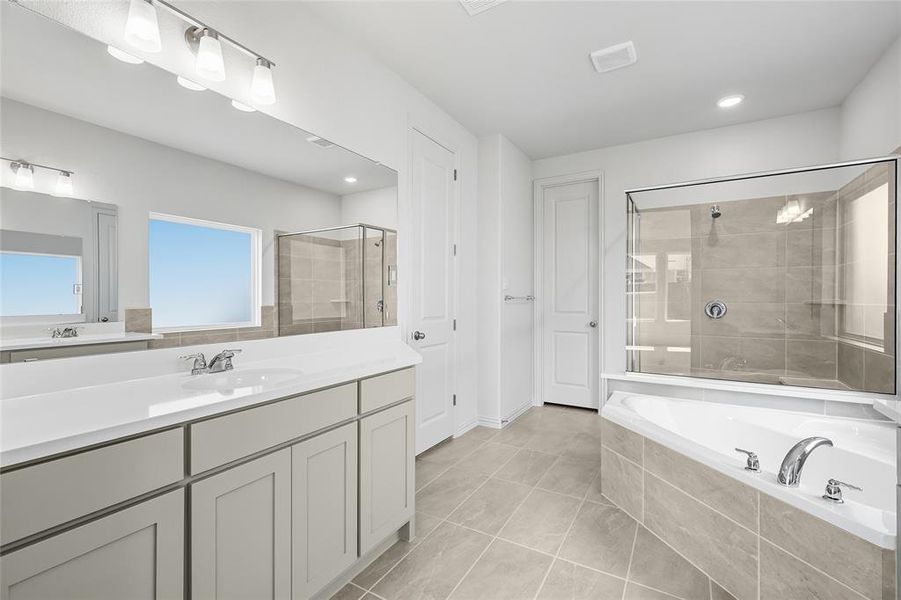 Full bathroom with a stall shower, vanity, a garden tub, and light tile patterned floors Full bathroom with a stall shower, vanity, a garden tub, and light tile patterned floors