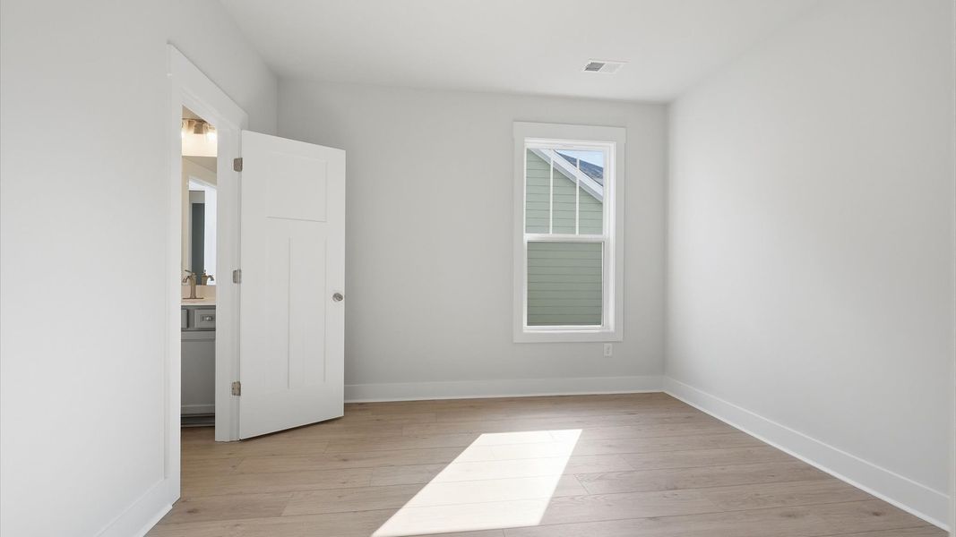 Bright and serene bedroom with comfortable hardwood floors and a large window for vibrant light near Lake Hartwell