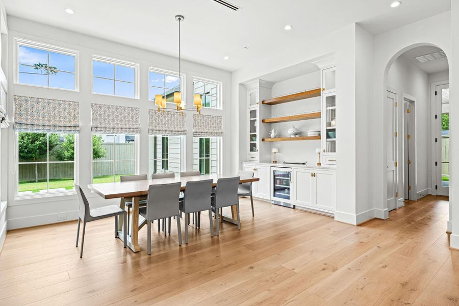 Positioned between the family room & kitchen, this charming breakfast space offers a seamless flow ideal for entertaining and everyday meals. A built-in serving bar w/ Taj Mahal quartzite countertops, glass-front cabinetry & floating display shelves adds both function & visual interest, while expansive windows bring in abundant natural light. Positioned between the family room & kitchen, this charming breakfast space offers a seamless flow ideal for entertaining and everyday meals. A built-in serving bar w/ Taj Mahal quartzite countertops, glass-front cabinetry & floating display shelves adds both function & visual interest, while expansive windows bring in abundant natural light.