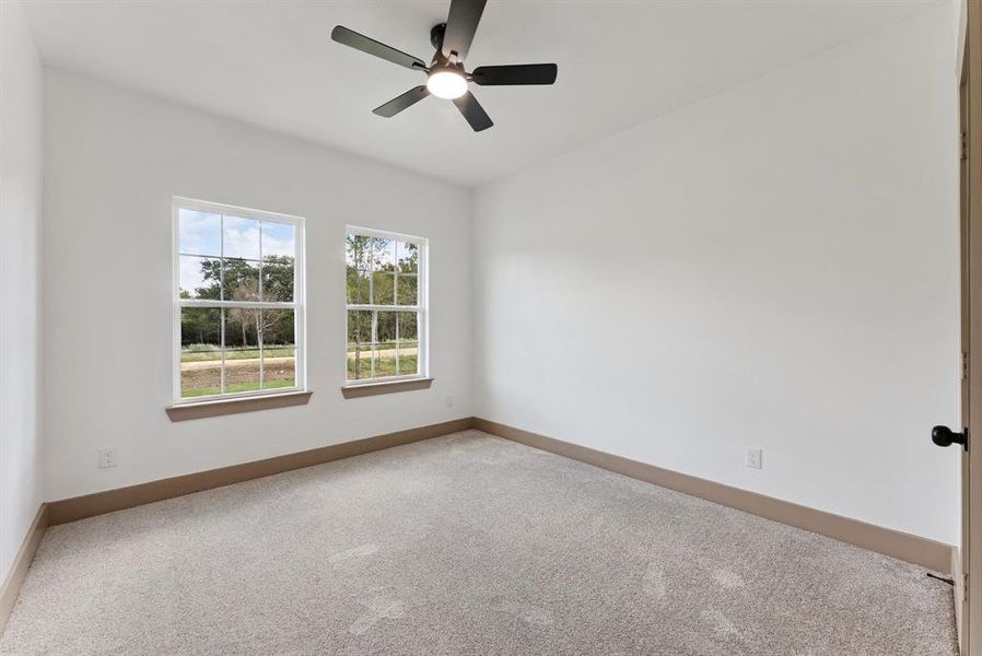 Carpeted spare room with baseboards and ceiling fan Carpeted spare room with baseboards and ceiling fan