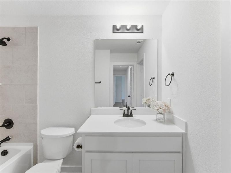 White vanity with an integrated sink, black-finish faucet, and a large wall-mounted mirror White vanity with an integrated sink, black-finish faucet, and a large wall-mounted mirror