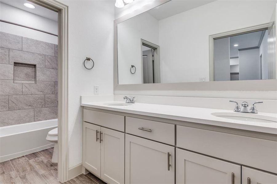 Full bathroom with double vanity, light wood finished floors, shower / washtub combination, and recessed lighting Full bathroom with double vanity, light wood finished floors, shower / washtub combination, and recessed lighting