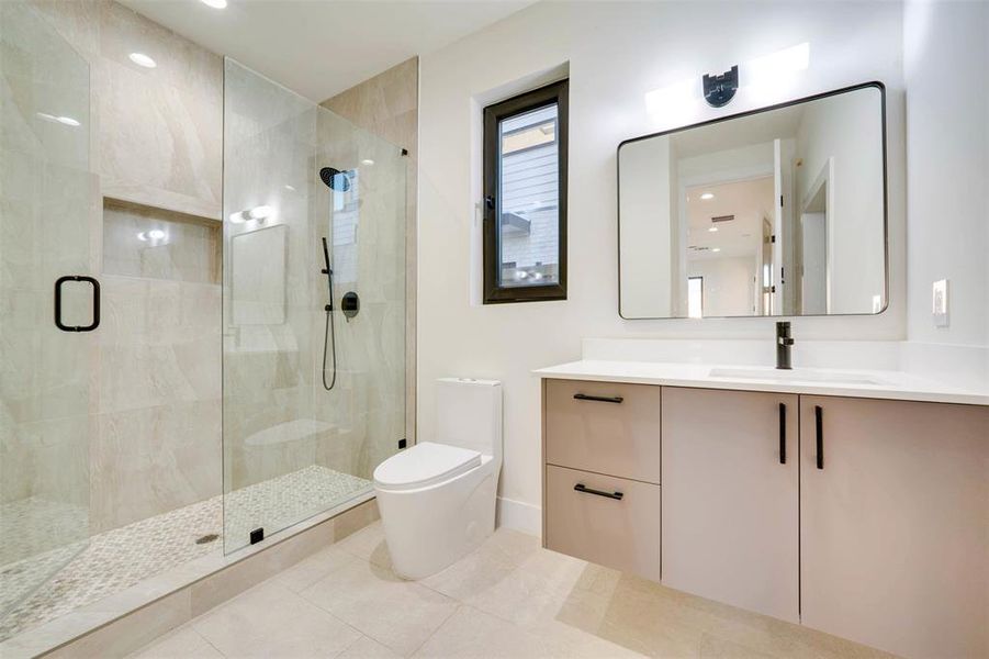 Bathroom featuring vanity, toilet, tile patterned flooring, and walk in shower