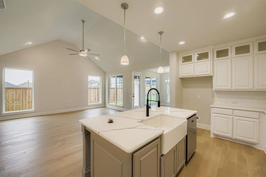 Kitchen with light wood-style floors, plenty of natural light, pendant lighting, an island with sink, and recessed lighting