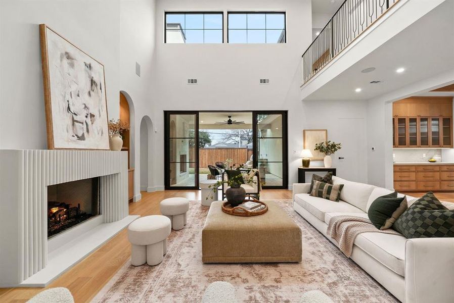 Living area with a lit fireplace, wood finished floors, arched walkways, recessed lighting, and a ceiling fan Living area with a lit fireplace, wood finished floors, arched walkways, recessed lighting, and a ceiling fan