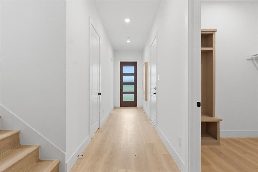 Entryway featuring a contemporary dark wood door with three lites, wood-finish flooring, recessed lighting, and a built-in light wood storage unit with shelving and bench Entryway featuring a contemporary dark wood door with three lites, wood-finish flooring, recessed lighting, and a built-in light wood storage unit with shelving and bench